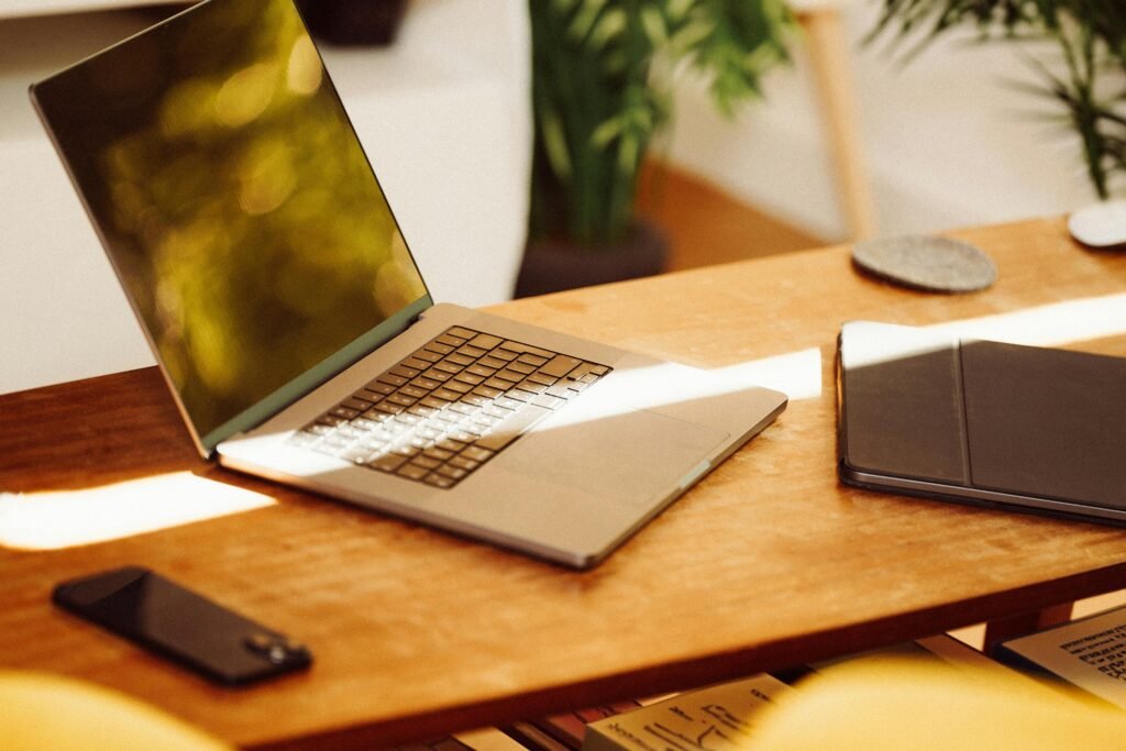 A cozy home office setup with a laptop, smartphone, and tablet on a wooden desk indoors.